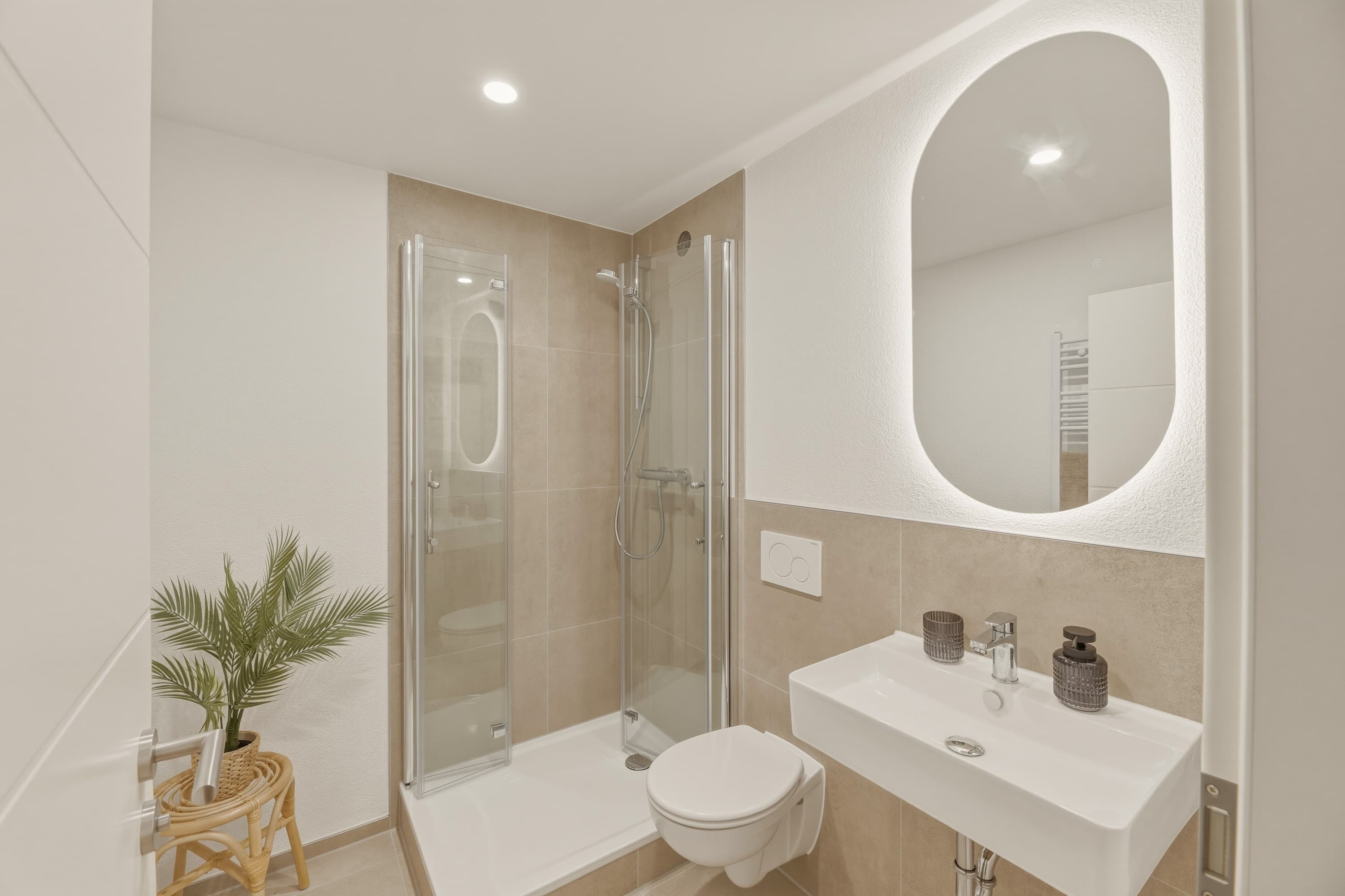 Modernisiertes Badezimmer mit Dusche und beleuchtetem Spiegel