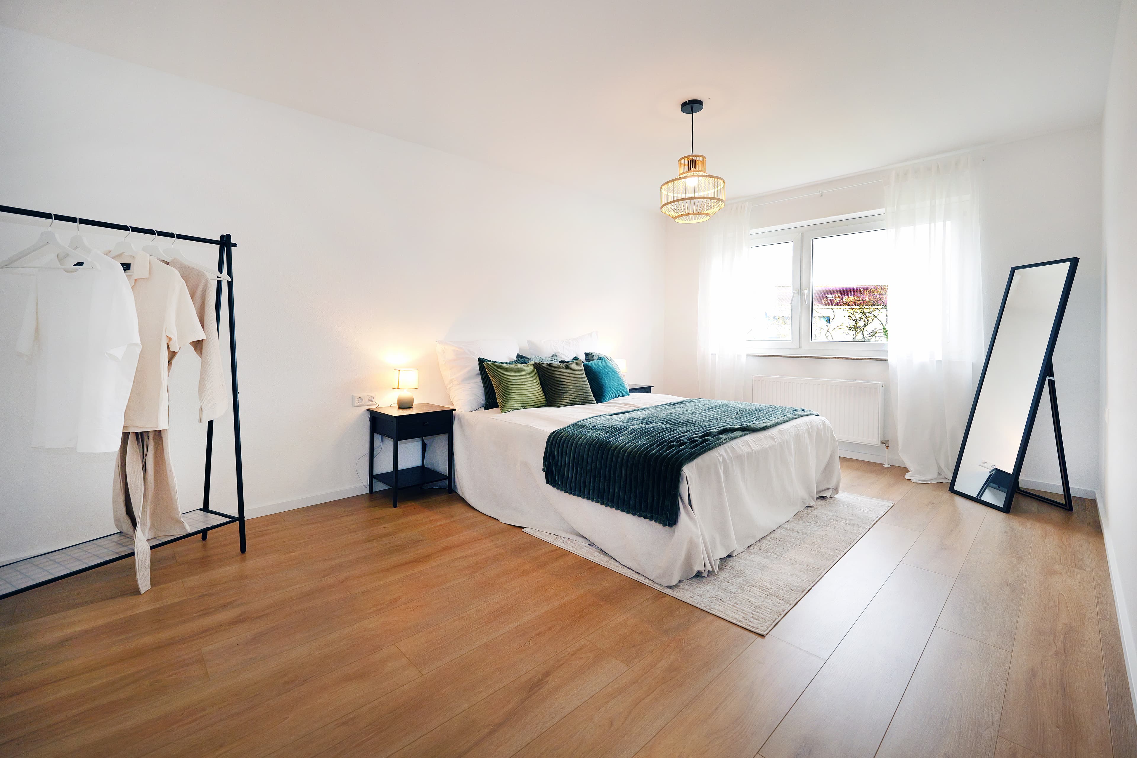 Schlafzimmer mit Doppelbett, Holzboden und großem Spiegel