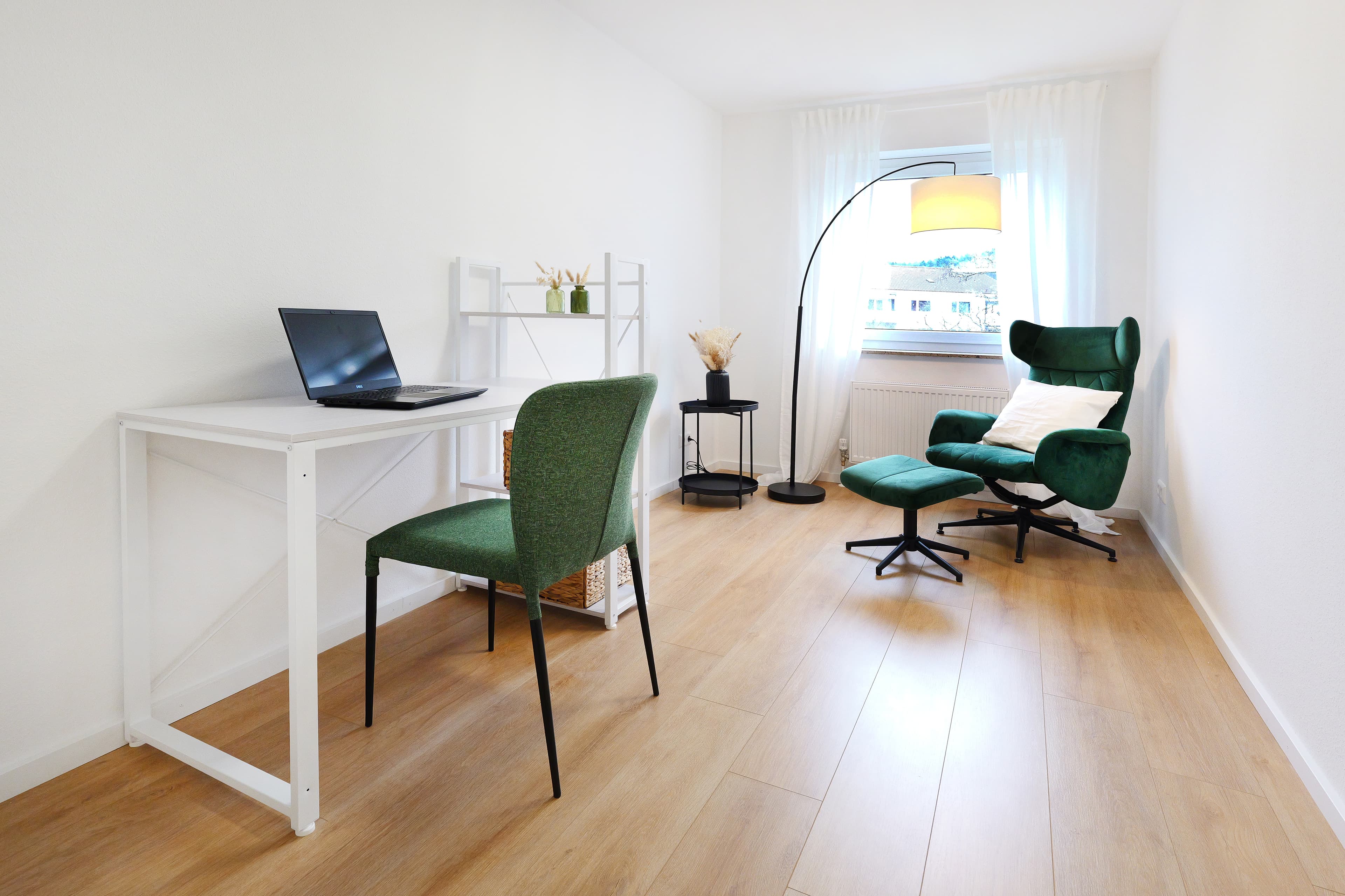Helles Arbeitszimmer mit Schreibtisch und grünem Lesesessel