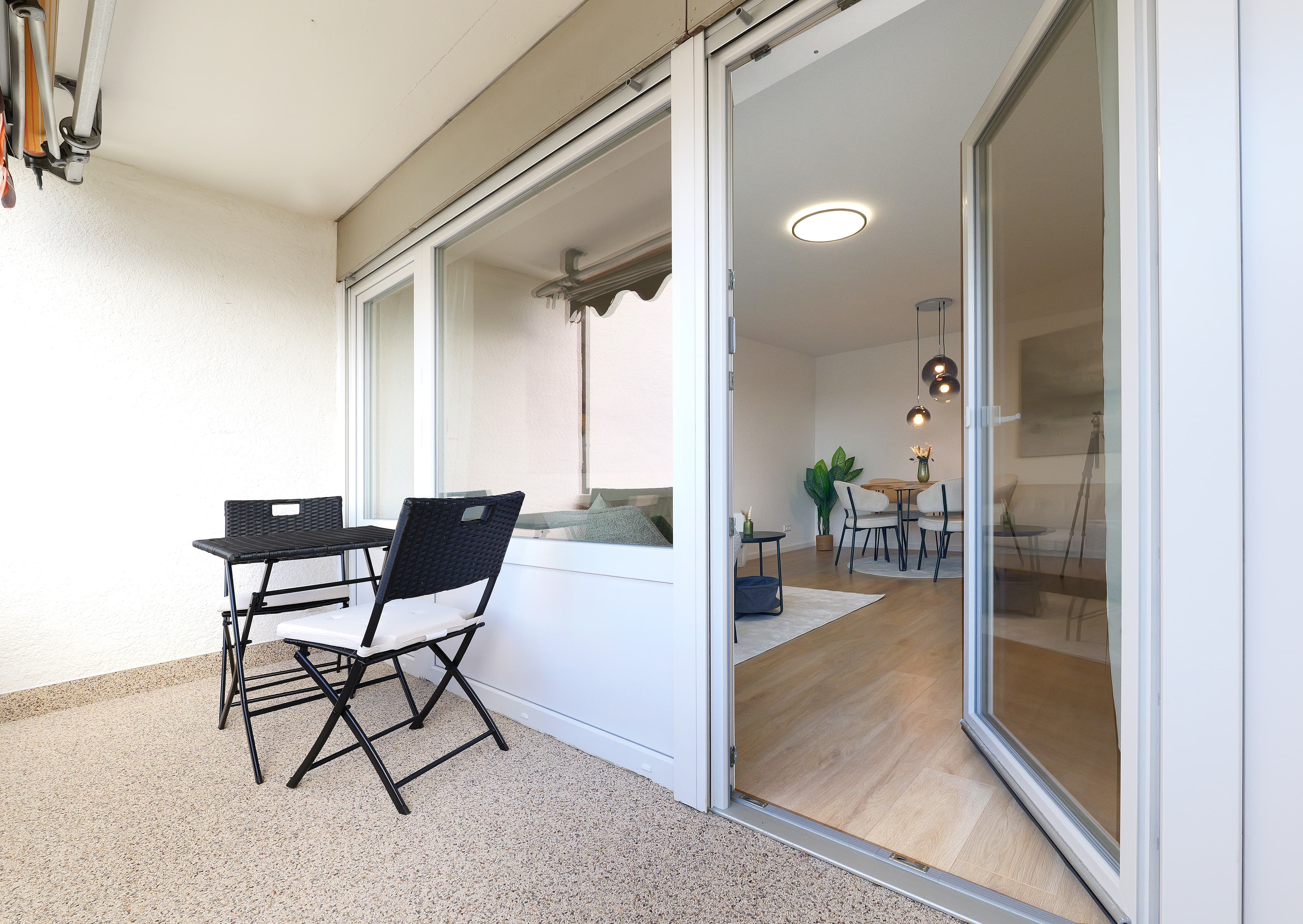 Überdachter Balkon mit Sitzplatz und Blick in die Wohnung