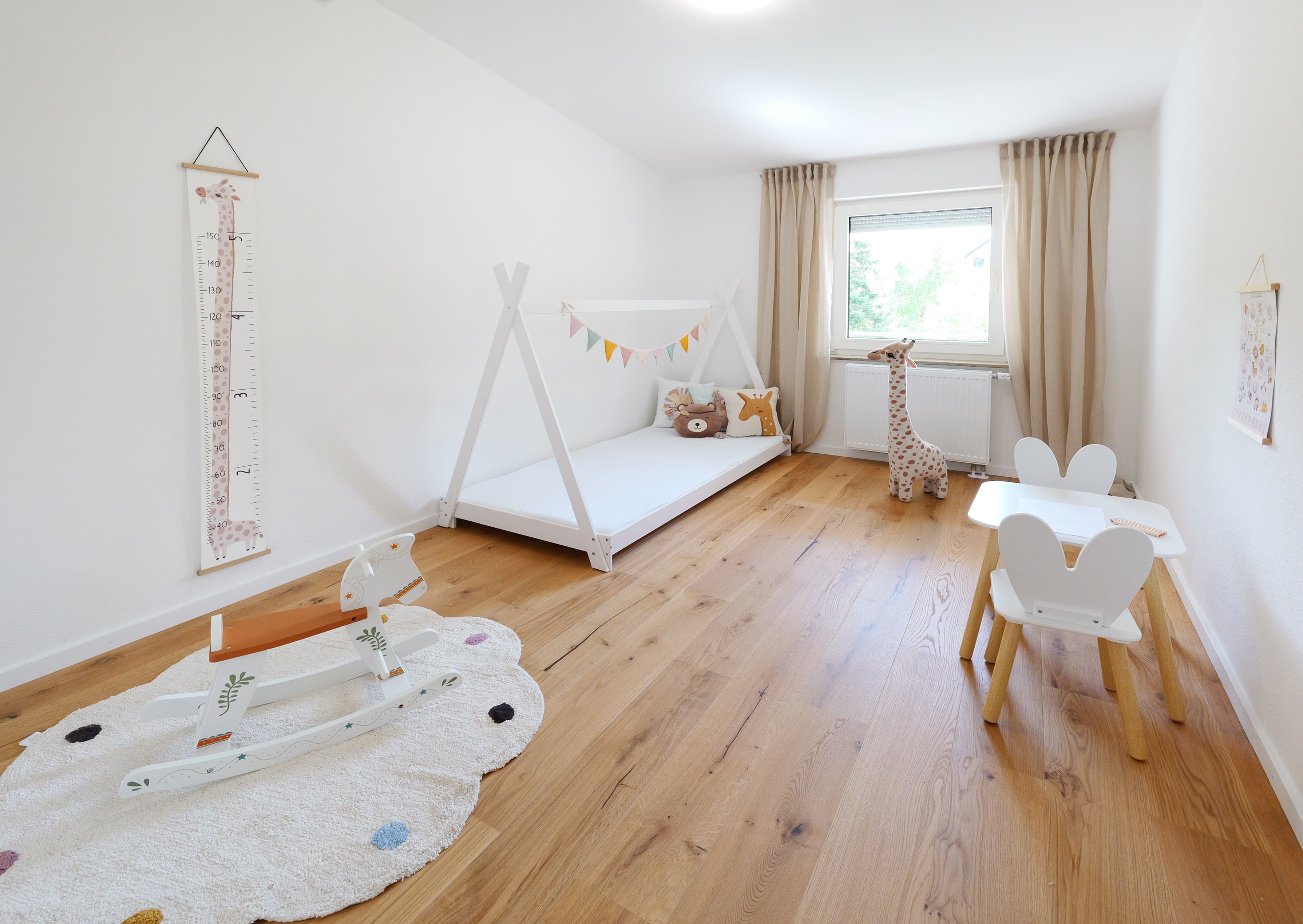 Liebevoll eingerichtetes Kinderzimmer mit Holzboden und großem Fenster