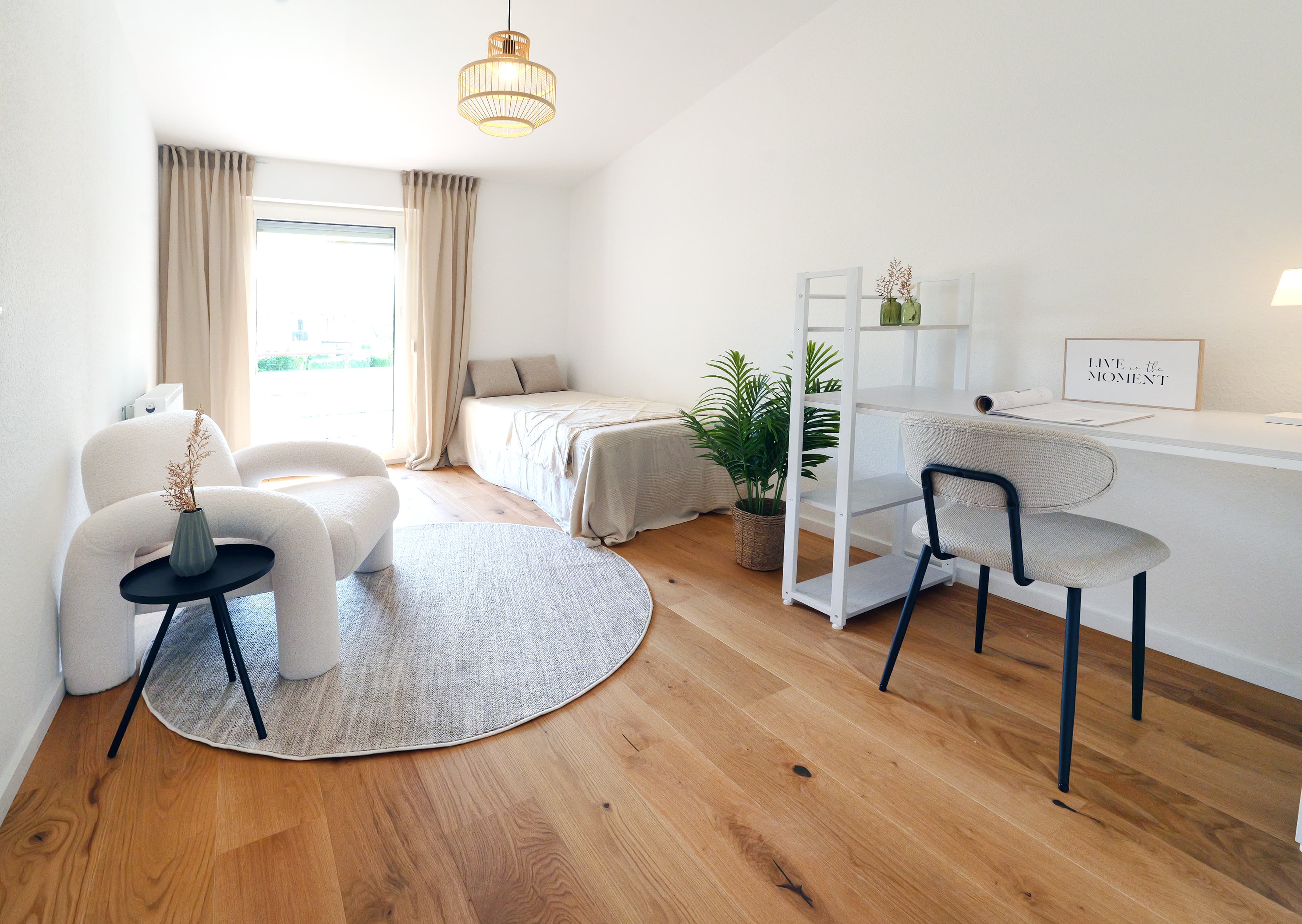 Helles Gäste- und Arbeitszimmer mit Bett, Sessel und Schreibtisch